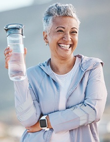 Woman smiling with water bottle on hike outside