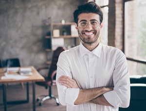 Man with dental bridge smiling with arms crossed