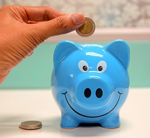 Hand putting coin in blue piggy bank