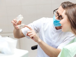 Dentist and patient looking at model discussing the price of dental implants in Friendswood