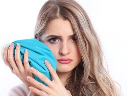 young woman holding ice pack on sore jaw