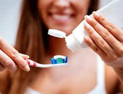 woman putting toothpaste on toothbrush