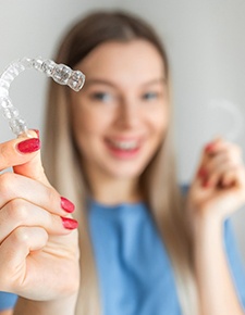 Woman holding a pair of aligners for Invisalign in Friendswood, TX