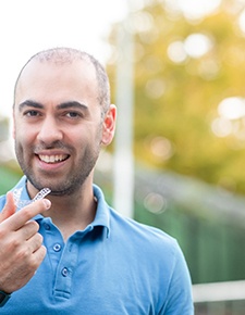 Man in blue shirt holding aligner for Invisalign in Friendswood, TX