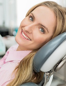 Woman with porcelain veneers smiling in dentist chair