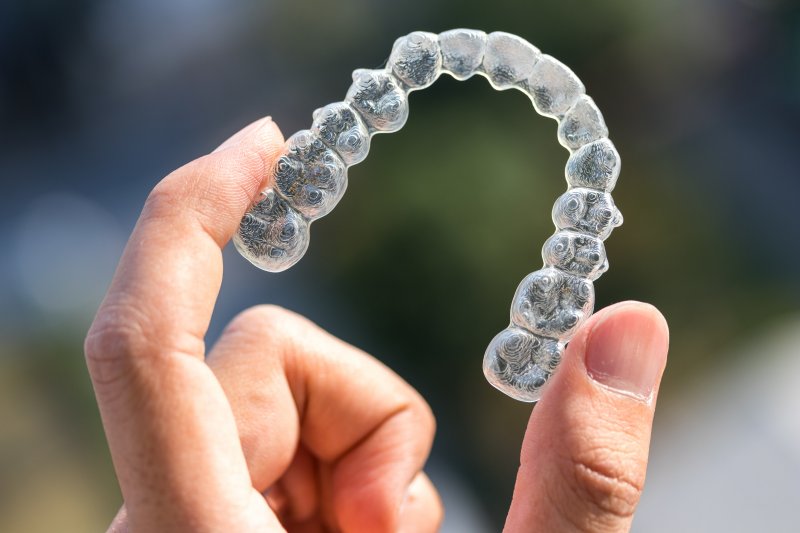 woman's hand holding invisalign aligner