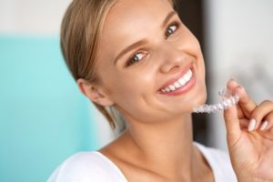 Woman holding Invisalign clear aligner