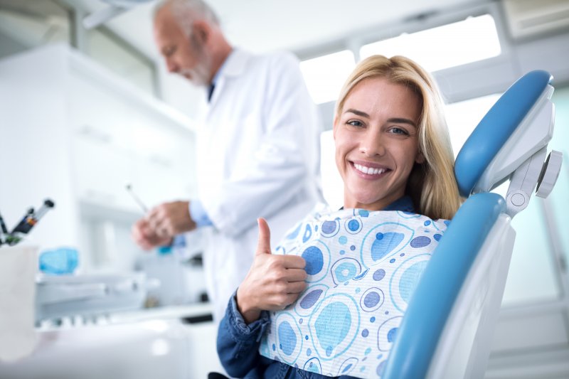 Woman smiling and giving thumbs up in treatment chair