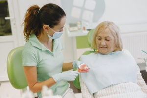 Dentist discussing denture care with female patient
